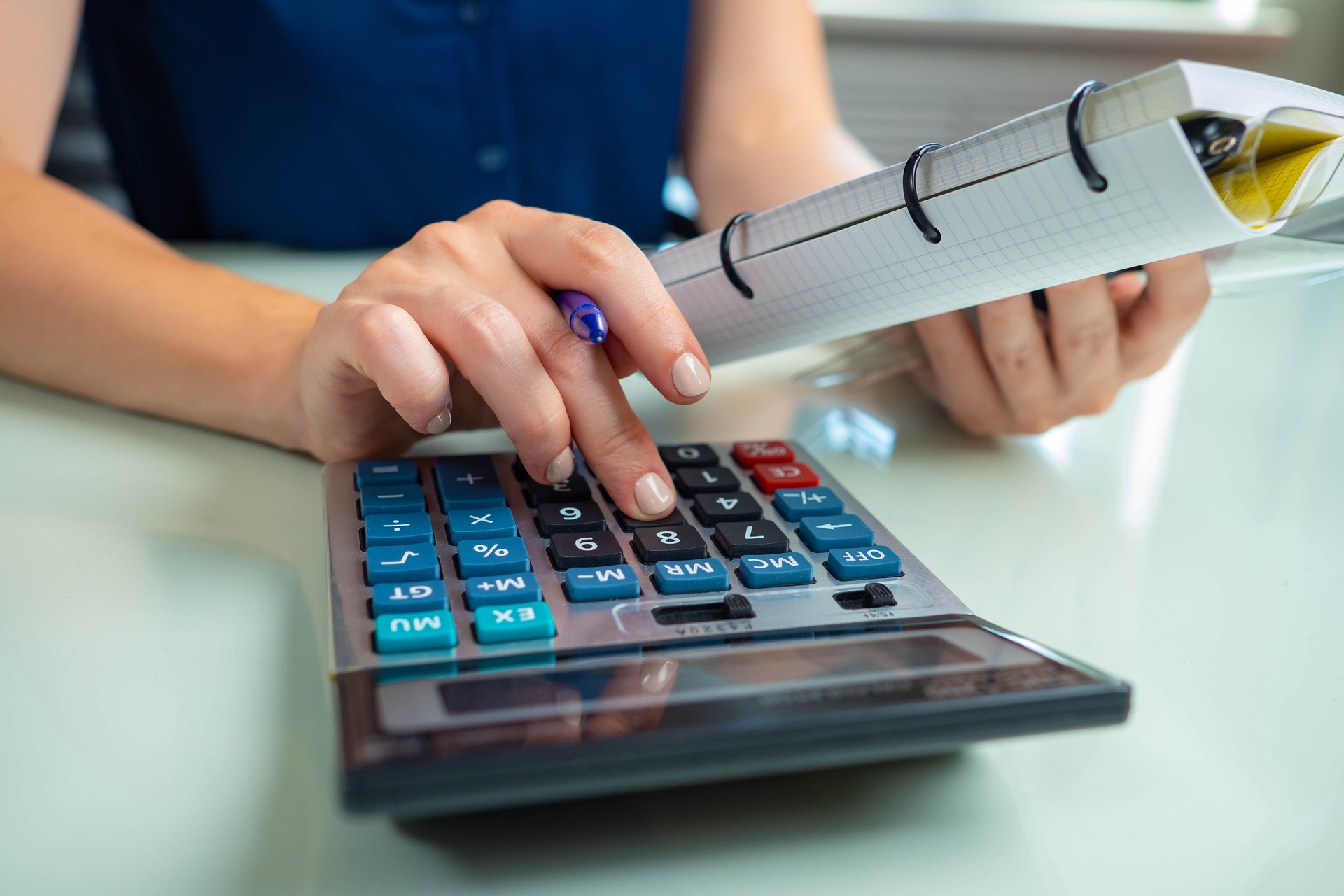 Woman works as an accountant. Person counts on calculator. Woman keeps accounting and tax records. Counting money, financial calculations, budget management. Businesswoman with notebook and calculator